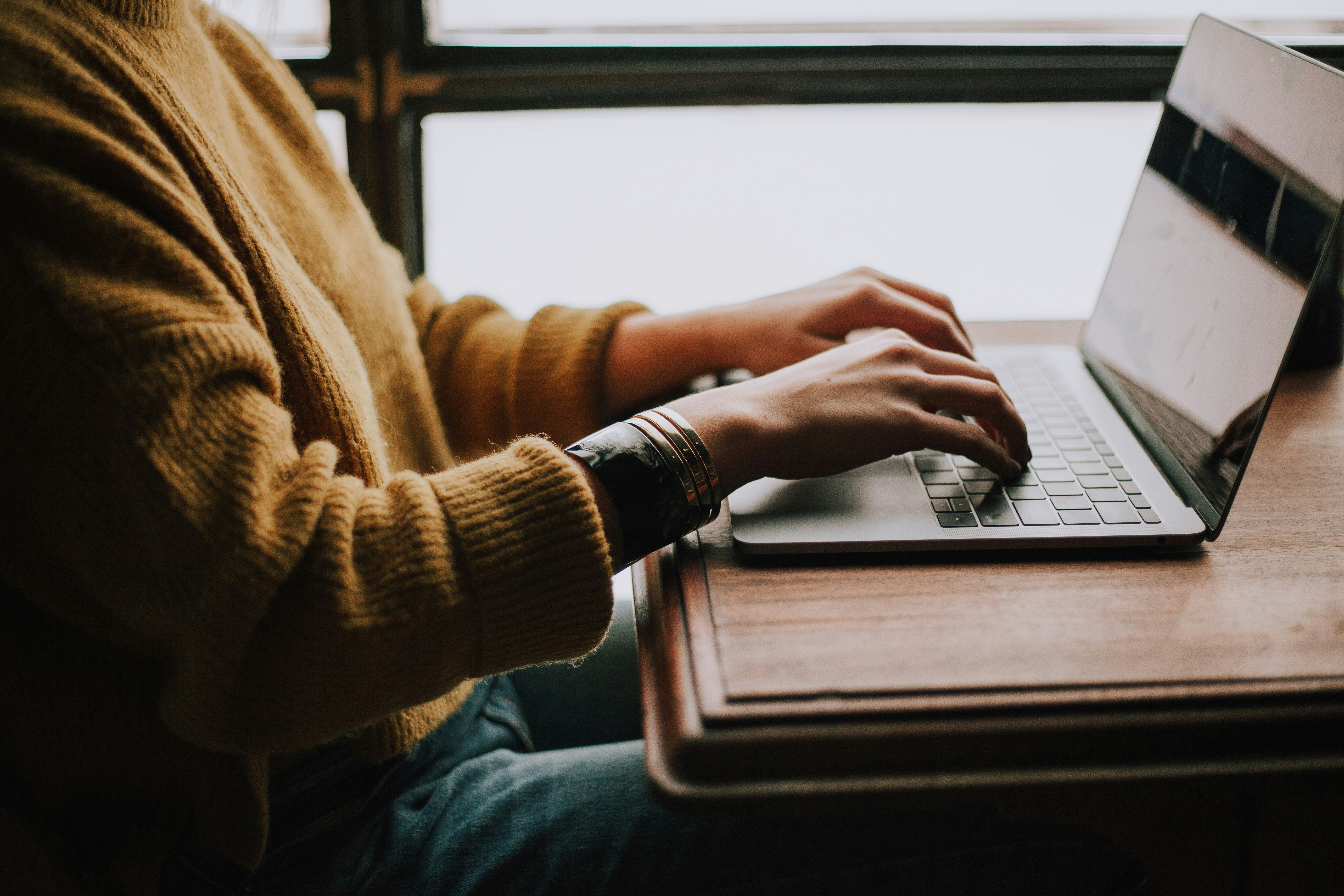 Hands of person typing on laptop