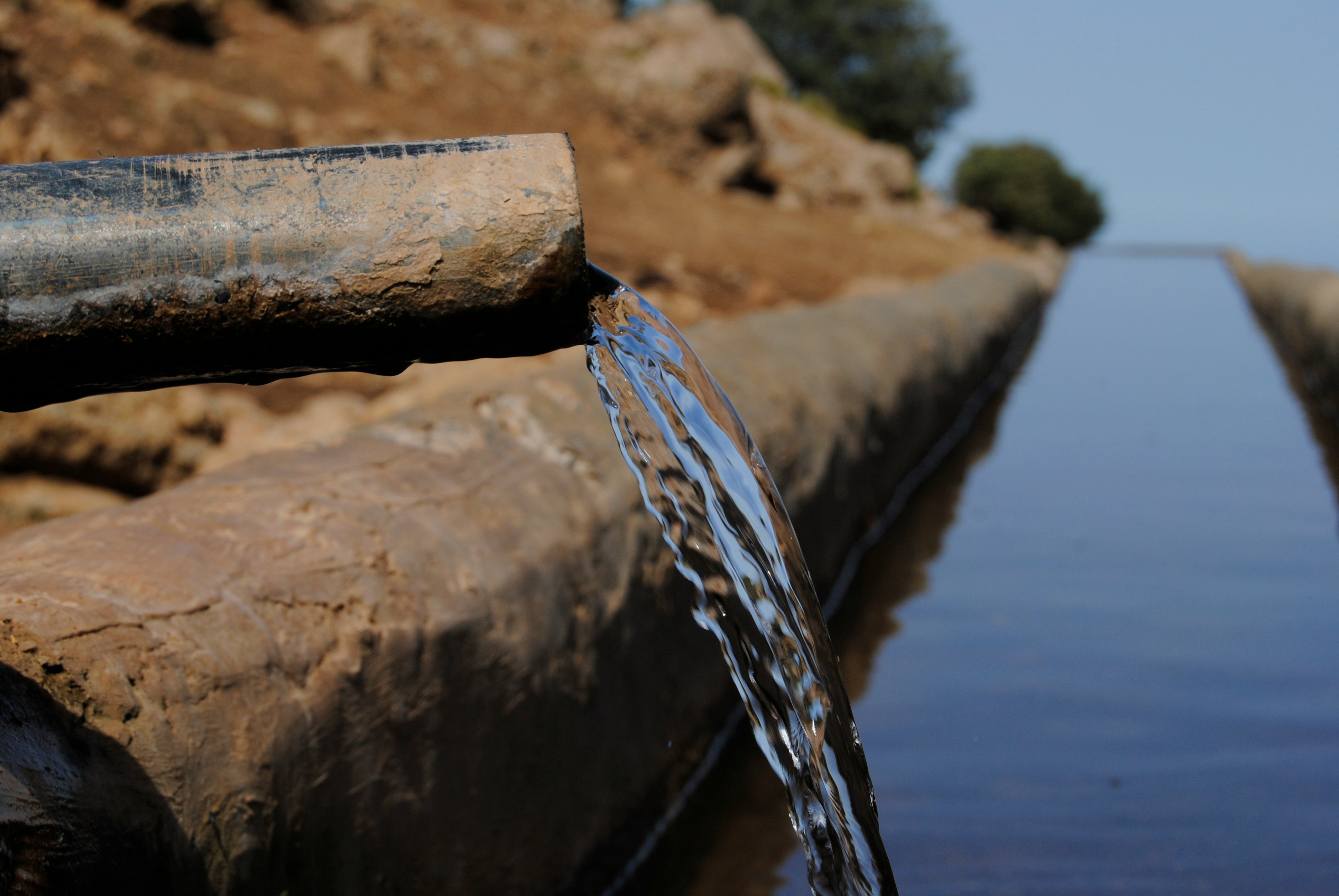 Image of a pipe with water flowing out into a body of water