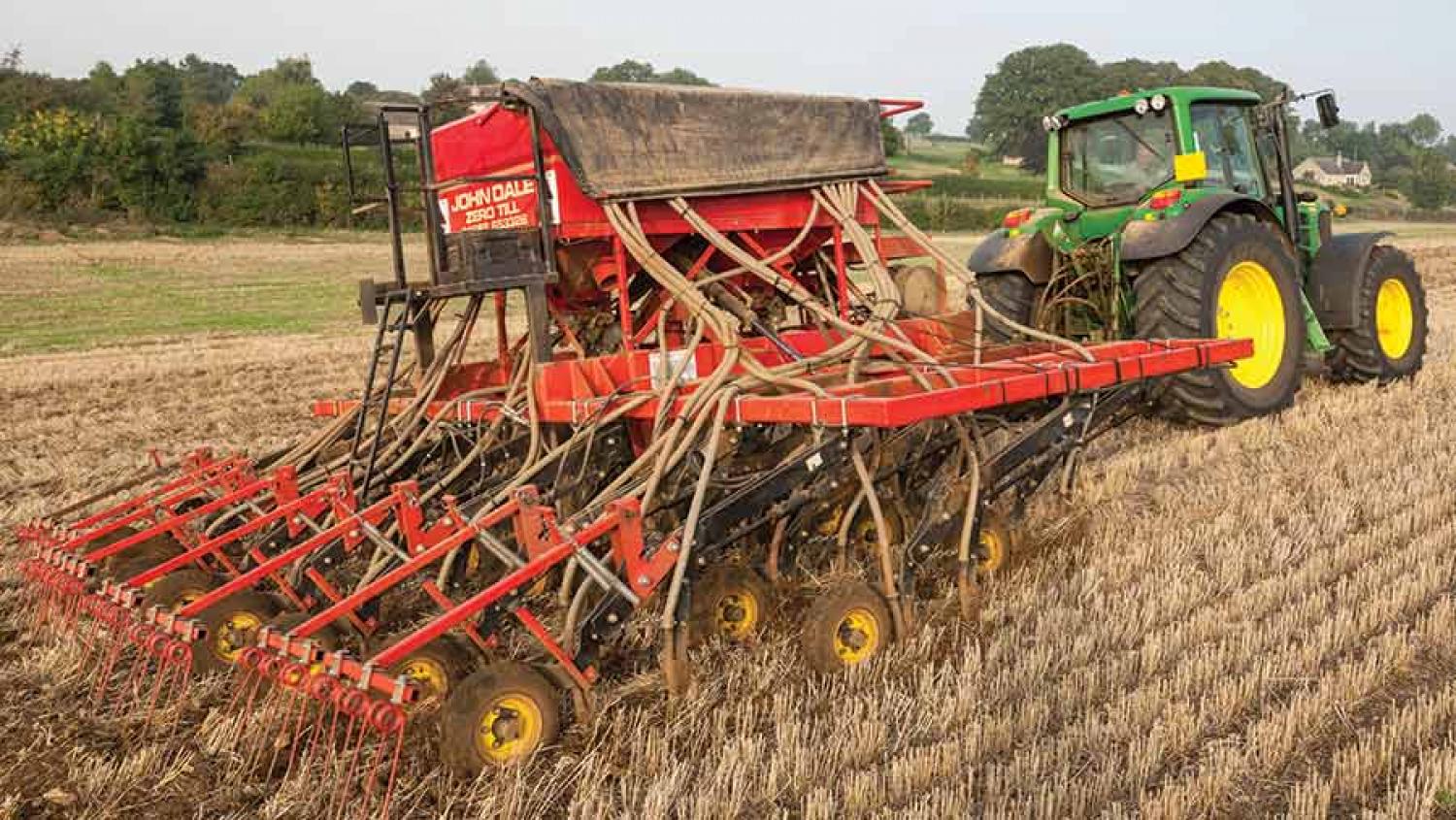 A John Deere tractor pulling a direct drill through a field of stubble