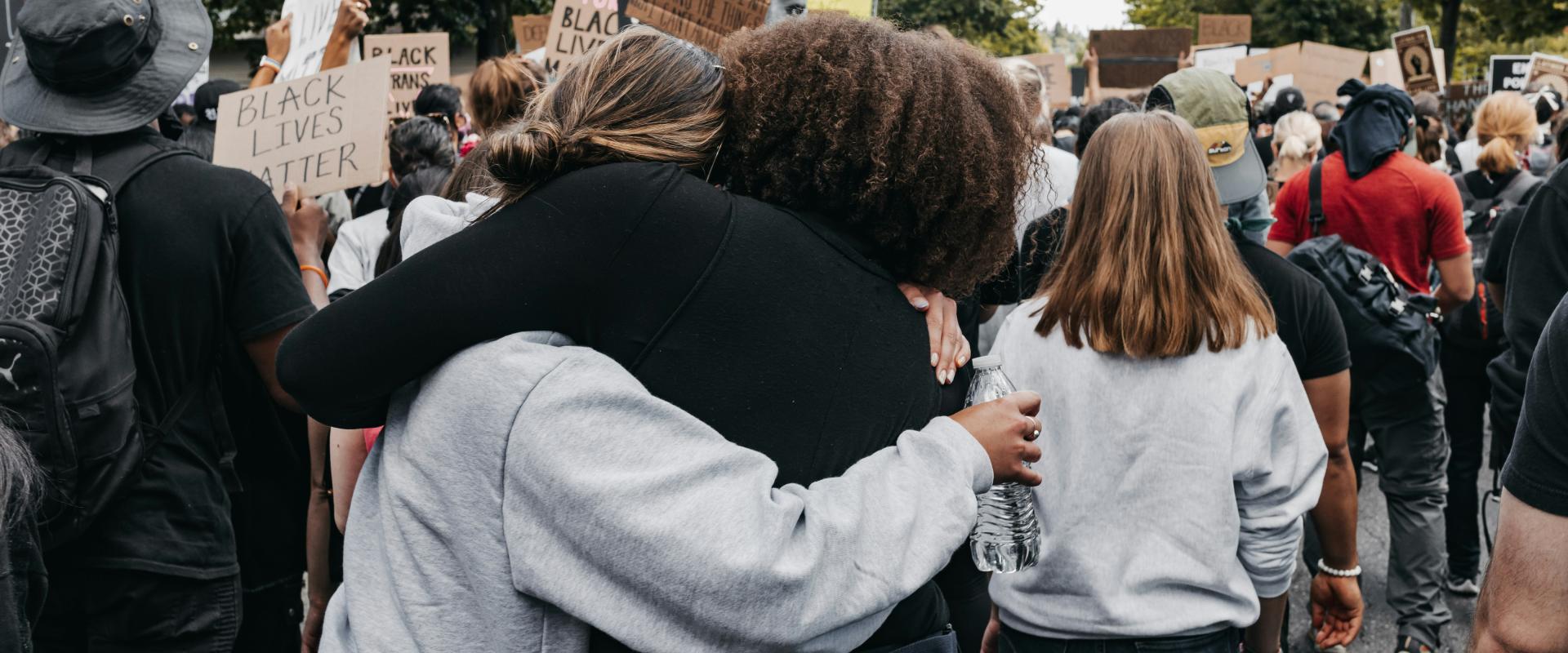 Image of two people embracing at a protest.