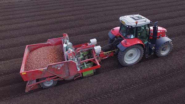 A drone's eye view of a root crop planter, pulled by a tractor as it works in the field